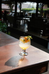 Refreshing citrus drink with mint garnish on sunlit patio, perfect for summer promotions or restaurant menus, evoking relaxation and vibrant flavors