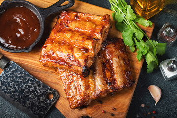 Spicy hot grilled spare ribs from a summer BBQ served with a hot chili pepper and fresh tomatoes