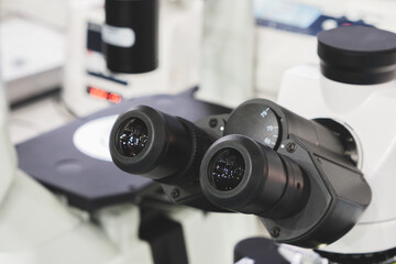 Close-up of microscope eyepieces in biological or scientific medical laboratory analysis, scientific medical concept background in blue tones