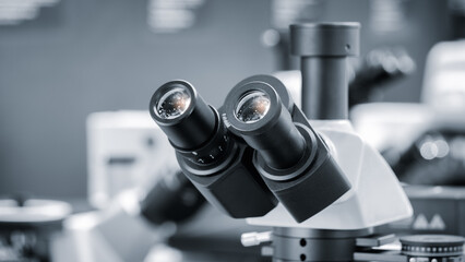 Close-up of microscope eyepieces in biological or scientific medical laboratory analysis, scientific medical concept background in blue tonesю