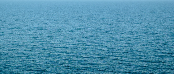 Wide panorama of blue clear sea water surface as background for web banner template page design or wallpaper.