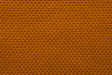 Closeup of orange knit fabric texture with warm yarns and cozy pattern background