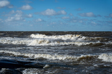 Large whitehead ocean waves crashing to shore on a sunny day.