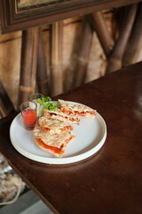 Delicious quesadilla slices with fresh herbs and dipping sauces on wooden table, perfect for restaurant menus or food blog promotions