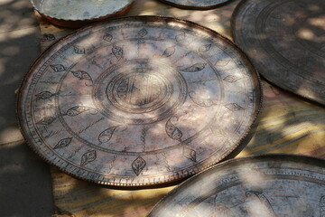 Antique copper trays and dishes with detailed engraving displayed at a flea market in Tbilisi. Warm...
