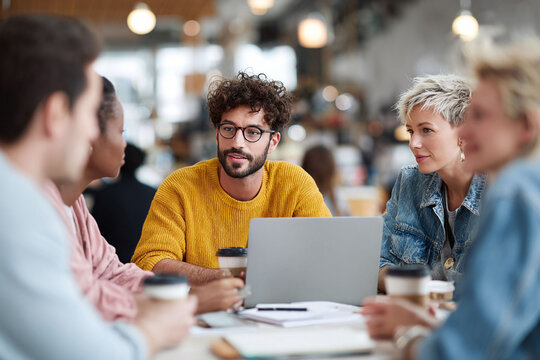 Diverse team collaborating on a project. Group of young professionals brainstorming ideas, working together in a modern, bright office space. Represents teamwork and innovation.