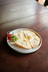 Crispy cheese flatbread with vibrant tomato dipping sauce and fresh parsley garnish for a delicious appetizer or snack on a rustic wooden table