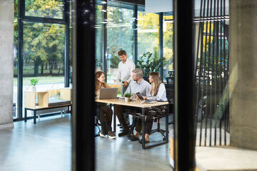 Business office with people casual wear, with blurred bokeh background, view from glass wall