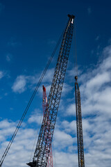 Fototapeta premium large cranes against blue sky with clouds