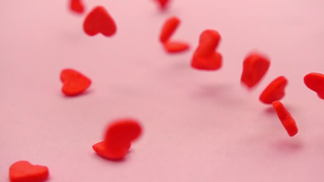 vibrant heart shaped sprinkles fall gently on soothing pink surface, perfect for adding romantic touch to party themes and celebrations, concept St Valentine day, super slow motion, macro