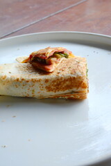 Delicious breakfast wrap with fresh vegetables and ham ready to be enjoyed on a light plate for a quick start to your busy morning