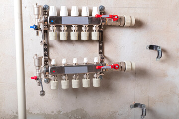 Modern plumbing distribution manifold installed on a concrete wall in a residential building's utility area