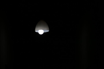 bright lamp hanging down from the ceiling in complete darkness of a living room