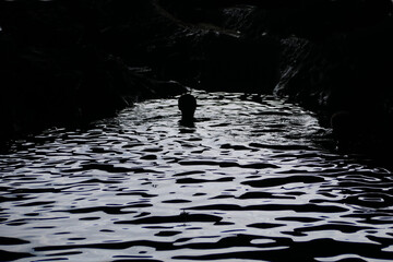 high contrast black water surface with a single person swimming in the pool 