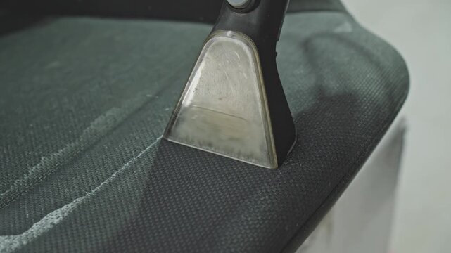 Person cleaning car seat using washing vacuum cleaner. Watch as dirt and stains disappear from car seats, revealing a fresh and clean interior. Transforming dirty car seats. Close-up in 4K, UHD