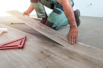 Floating floor work. The worker inserts the board of vinyl plank to the click system of Floating floor.