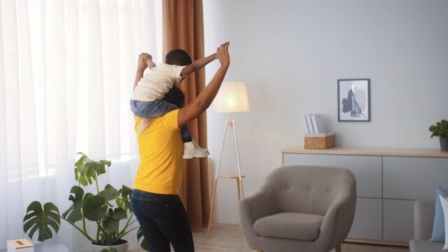A loving mother carries her young son on her shoulders as they play together in a bright and spacious living room. The atmosphere radiates warmth and affection.