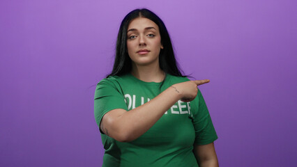 Obraz premium Woman making a gesture to leave with finger pointing over a purple background wearing a green volunteer shirt, expressing confidence and assertiveness.
