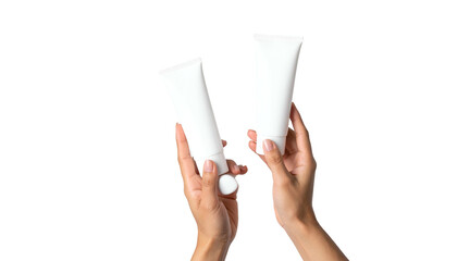 Two hands hold up white cosmetic tubes against a stark black background
