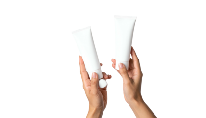 Two hands hold up white cosmetic tubes against a stark black background