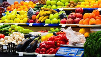 Bright counter with beautifully laid out fresh fruits and vegetables in a supermarket or market and electronic scales for weighing products.