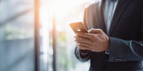 Businessman in suit holding smartphone with lock icon, symbolizing mobile security, data protection and cybersecurity in modern digital communication.