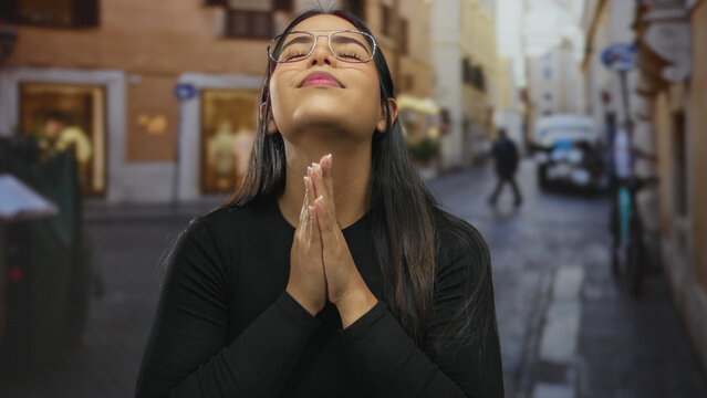 Young woman meditating on a street outdoors with a pensive expression wearing glasses and a black outfit