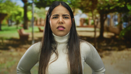 Woman face shows confused look in park with young latin hispanic attire standing in green outdoors...