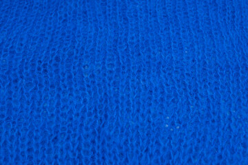 Macro shot of blue knitted wool fabric with visible fibers. Soft warm texture perfect for winter fashion, design, or cozy textile backgrounds. Natural yarn material close up.
