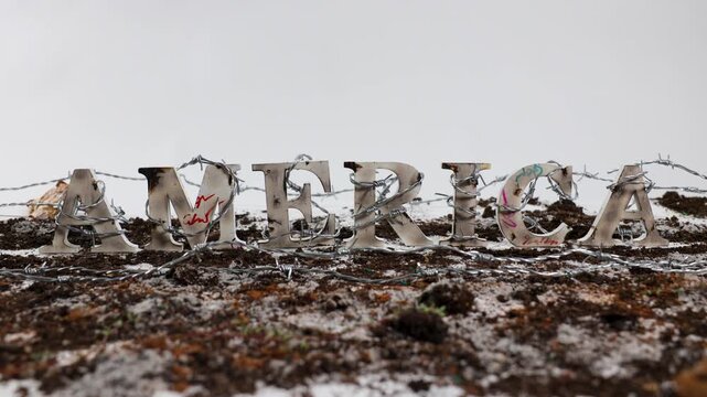 Barbed wire wraps around the word America against white backdrop