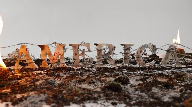 Barbed wire wraps around the word America against white background