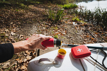 Outdoor Adventure Picture enjoying a warm drink from a thermos by the serene lakeside, immersing...