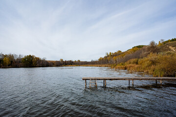 Naklejka premium In the center of a picturesque lake, there is a beautifully crafted wooden dock that extends into the tranquil water, providing a perfect spot for relaxation and enjoying nature