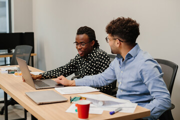 Diverse business professionals collaborating on laptop in modern office