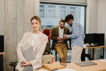 Young businesswoman smiling, holding laptop in office