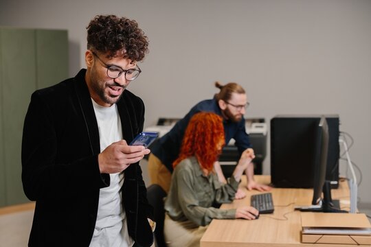 Young professional using mobile phone in modern business office - Powered by Adobe