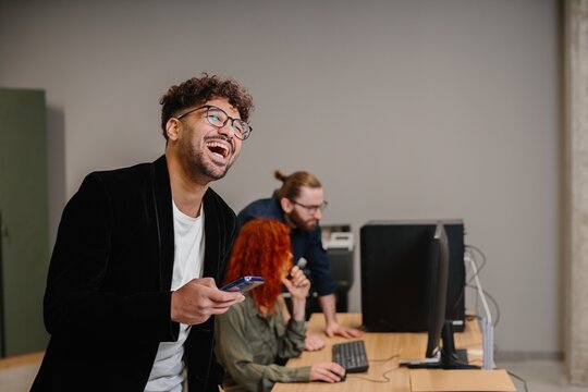 Happy business man laughing while holding phone