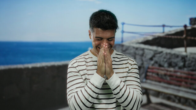 Young man smiling at seaside promenade with ocean background on a sunny day