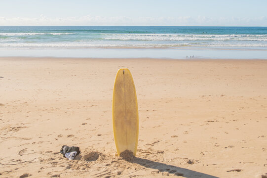 Yellow surfboard standing in sand on Atlantic beach. Caparica, Lisbon, Portugal. 2 December 2023.
