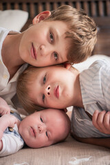 Three brothers lie close together, their heads gently touching, creating a warm and intimate family portrait