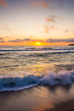 closeup of wave rolling on sandy shore at golden sunrise. cozy bamboo beach of sozopol at the black sea in summer. sun glowing over horizon. beautiful low angle vertical image for travel background
