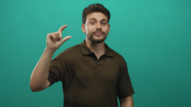 Man pinching thumb and forefinger to show small size with visible hand in teal studio; small scale confidence.