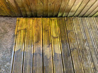 Before and after view of dirt and grime being cleaned from wooden decking using a pressure washer. DIY concept.