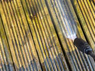 Before and after view of dirt and grime being cleaned from wooden decking using a pressure washer. DIY concept.