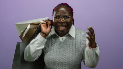 Woman smiling holding shopping bags over isolated purple background with joyful expression and surprise.