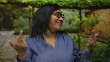 Woman wearing black glasses shows upraised extended middle finger while smiling in forest; defiance.