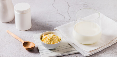 Colostrum powder in a bowl and a drink in a glass on a table web banner