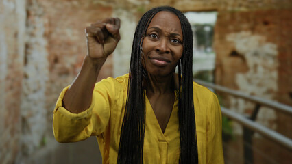 Woman with curly hair gestures in ancient roman ruins while wearing a yellow shirt, capturing a...