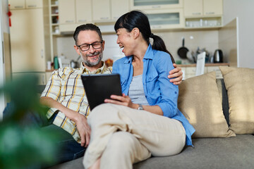 Portrait of a lovely young couple using a tablet computer together and having fun sitting on sofa...