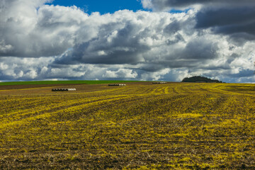 Dramatic Sky Over Plowed Farmland with Hay Bales